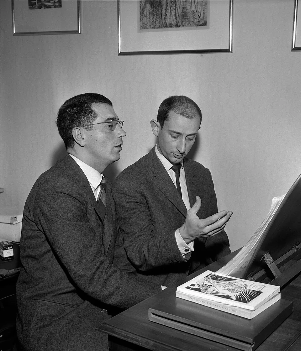 Profesor y alumno conversando junto a un piano durante una clase